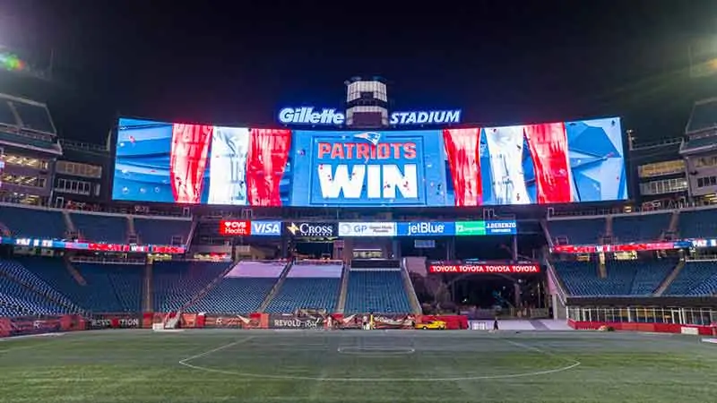 High-Brightness Giant LED Display in the Stadium - EagerLED | Leading LED Screen Supplier - EagerLED | Leading LED Screen Supplier Night view of Gillette Stadium with a giant screen that reads 'PATRIOTS WIN' at night, empty stands and a green field in front.