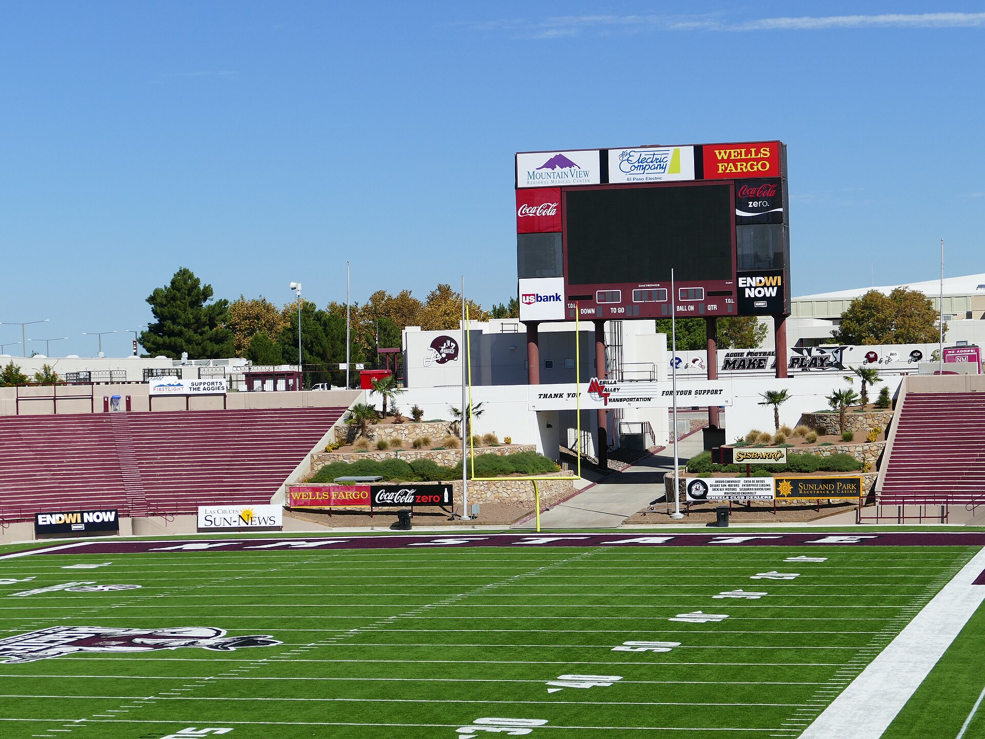 Stadium scoreboard video board above perimeter LED advertising boards at an American football venue